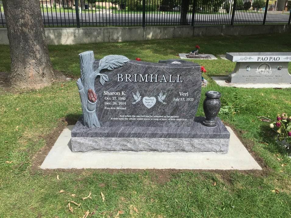 Grey granite upright with a fully carved tree trunk and leaf at one side