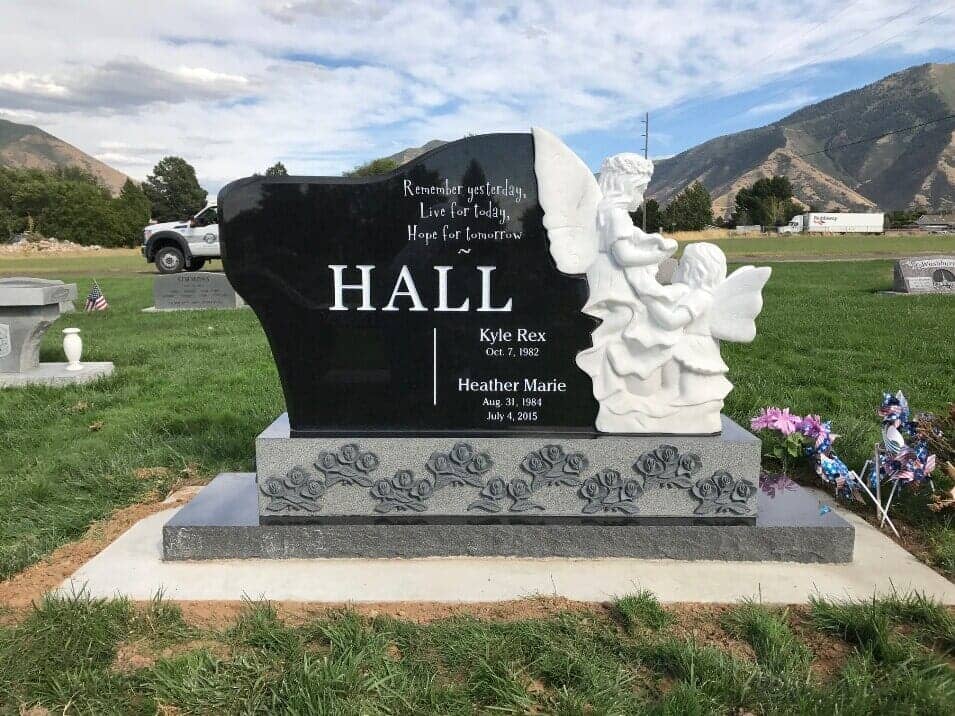 Black granite upright with carved white angels, the Wasatch mountains behind it