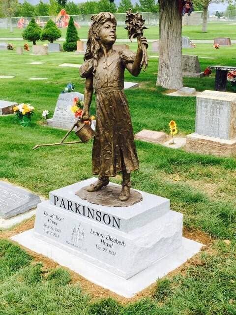 Bronze figure of a girl holding flowers on a light granite base