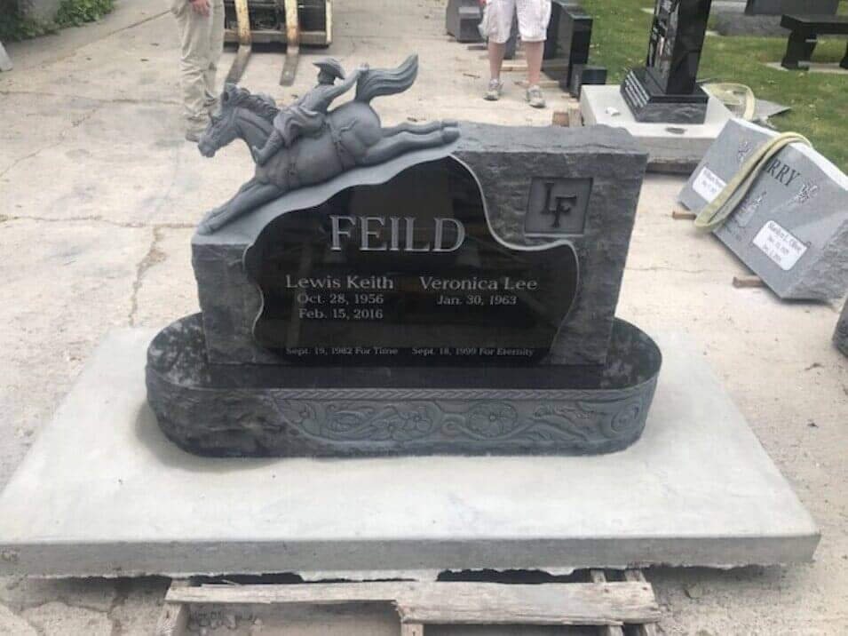 A carved granite horse and rider monument standing in the yard behind the shop
